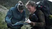 Zwei Personen überprüfen die Karte in einem Berggebiet.
