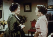 Mrs. Oleson (Katherine MacGregor, li.) erklärt Anna (Iris Korn, re.), dass sie durch ihre Liebe zu Reverend Alden dessen Stellung in der Kirche gefährdet.