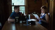 Amy reads papers at table with Adam looking on.