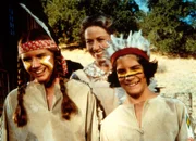 Albert Ingalls (Matthew Laborteaux, r.) und seine Schwester Laura (Melissa Gilbert, l.) stellen stolz ihrem Vater die Kostüme für den Maskenball vor. Mutter Caroline (Karen Grassle, M.) freut sich mit ihnen.