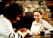 Caroline (Karen Grassle, r.) und ihr Mann Charles (Michael Landon, l.) überlegen, ob sie die schlafenden Kinder wecken sollen, da es Zeit wird , zum Maskenball zu gehen.