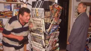 Benno (Willi Thomczyk, li.) hat sich ins Kiosk geschlichen, um heimlich den Schlüssel von den Herrenduschen zu holen. Doch er ist zu langsam. Als Pröter (Wilfried Herbst) kommt, um den Kiosk abzuschließen, kann sich Benno nur noch hinter dem Zeitungsständer verstecken.