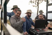 Jerry gives a thumbs up while Colin, Max, and Guillermo look at a computer.
