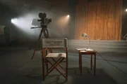 Der Stuhl des Regisseurs, die Kamera auf dem Stativ und die Lampe auf dem Tisch