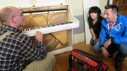 Auch das Klavier soll verkauft werden..  (Foto: Mona mit Mauro Corradino, re. und potentiellen Käufer, li.)