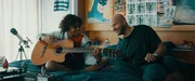 Thomas (Stan Van Samang) bringt Felix (Junes Callaert) auf der Gitarre den Lieblingssong von Marijke bei.