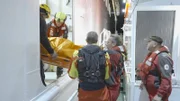 Seenotretter tragen Patienten von Kreuzfahrtschiff auf Seenotrettungskreuzer.