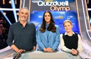 Quizmasterin Esther Sedlaczek (M.) begrüßt die Kandidat:Innen des Teams "Kulinarik": Christian Rach (l.) und Cornelia Poletto (r.).