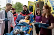 Nele Bader (Sarah Schmidt, M.) wird in Begleitung ihrer Freundin Bianka Schneider (Annemarie Hörold, 2.v.r.) in das Johannes-Thal-Klinikum eingeliefert.  Mikko Rantala (Luan Gummich, l.) und Tamar Hummel (Linda Kummer, r.) nehmen die Patientin vom Rettungsdienst (Komparsen, h.) entgegen.