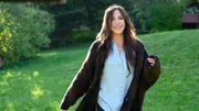 Katja Baumann (Simone Thomalla) steht fröhlich auf einer Wiese.