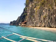 Coron, Philippinen: Holzhütten am Strand, die direkt an den Fels gebaut sind.