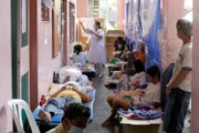 A nurse tends to typhoid fever patients gathered in the hallway of the crowded Jose Rizal hospital in Calamba, Laguna, the Philippines.
