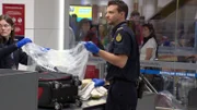 Beamte in Sydney sichern einer ankommenden Frau große Mengen verbotener Lebensmittel.