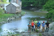 The Maine Cabin Masters are truly one of a kind as they pose in front of Bunganuc Creek in Brunswick, Maine where they are bringing an iconic cabin back to life, as seen on Maine Cabin Masters.