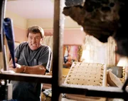 Hal (Bryan Cranston) zertrümmert wildentschlossen die Außenwand seines Schlafzimmers, um so ausreichend Platz für ein weiteres Kinderbettchen zu schaffen.