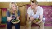 Reiseleiter Askan und Entertainmentmanagerin Cori kommen auf der Teeplantage ins Gespräch. Sie essen einheimische Spezialitäten.