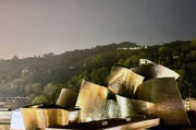 Die Metallfassaden der dynamisch aufgefalteten Dachlandschaft des Guggenheim Museums in Bilbao bestechen durch ihre Lichtreflexionen.