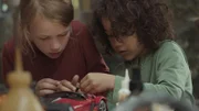 Saïd und Anna reparieren das Rennauto.