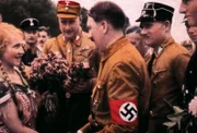 Reception: A flower girl greets Adolf Hitler in 1937, two years after Hannelore's encounter with the Nazi leader.