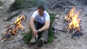Host Bear Grylls sits on the ground next to a fire in Cooper Canyon, Mexico.