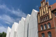 In Volumen und Traufhöhe orientiert sich der moderne Baukörper an seinem neogotischen Nachbarn.