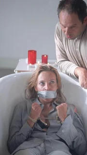 Dr. Thaler (Roswitha Meyer) ist in der Badewanne des Hotelzimmers, gefesselt und geknebelt, der Gewalt des Kai Kossak (Michael Lott) hilflos ausgeliefert.