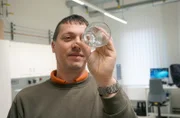 Erfinder Martin Groß mit einem ausgehärteten Trinkglas. Im Vergleich mit normalem Glas sind seine Gläser viermal so fest