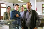 Die Cops (Igor Jeftic, 2.v.l.; Michael A. Grimm, 2.v.r.) glauben, dass Ehemann Gruber (Hannes Ringlstetter, r.) seine Frau vergiftet hat, nachdem er von der Affäre mit Windisch (Thomas Birnstiel, l.) erfahren hat.