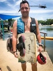Kapitän Robert Fronenbroek mit einem Wakeboard unter dem Arm. In Cairns, Australien, unternimmt der Kapitän mit Bordarzt Dr. Winfried Koller einen Ausflug zu einer Wakeboarding-Anlage.