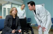 Sylvia Haas (Nina Weniger, li.) kommt mit einer Schnittwunde unter dem Auge, die angeblich von einem heruntergefallenen Bild stammt, in die Sachsenklinik. Dr. Philipp Brentano (Thomas Koch, re.) will die Wunde behandeln und bittet Schwester Miriam (Christina Petersen, mi.) einen Rollstuhl zu bringen. Sylvia scheint sehr wackelig auf den Beinen zu sein.