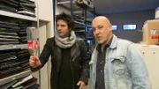 Die Versicherungsdetektive Ralph Schweda und Patrick Hufen (l.) rekonstruieren mit einer Plastikflasche die fragliche Situation, die zur Beschädigung des Fernsehers geführt haben soll.