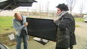 Die Versicherungsdetektive Ralph Schweda und Patrick Hufen (r.) rekonstruieren den fraglichen Schadenfall mit einem Fernsehgerät.