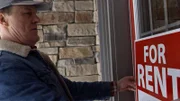 Ein Mann stellt ein Schild zum Verkauf auf