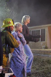 Jessica (Tracey Needham, r.) und Großmutter Martha (K. Callan) konnten von der Feuerwehr (l. Darst. unbekannt) aus dem brennenden Haus gerettet werden, doch für Jessicas Tochter kommt jede Hilfe zu spät.
