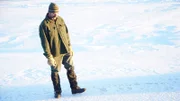 Ray Lewis inspecting animal prints near his cabin.