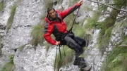 Bear Grylls abseiling down rock face.