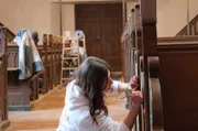 Maler-Auszubildende Alina Schwabke lernt in der Bernitter Dorfkirche, wie historische Kirchengestühle fachgerecht erneuert werden.