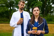 Der Assistenzarzt Dr. Wiesner (Pablo Konrad l.) muntert Sofia (Kiara Brunken, r.) bei einem gemeinsamen Kaffee im Klinikpark wieder auf.