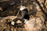 Marty Raney digging foundations for the underground greenhouse with a shovel at the Ettinger Homestead in Wolf Creek, Montana.