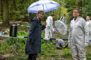Der Banker Erik Thiel (Komparse, liegend) wird mit seiner eigenen Waffe erschossen im Wald aufgefunden. Der ersten Kriminalkommissarin Martina Seiffert (Astrid M. Fünderich, l.) stellen sich drängende Fragen: Was führte den Mann in den Wald? Fühlte er sich bedroht, oder warum hatte er die Waffe bei sich? Für den Leiter der KTU Jan Arnaud (Mike Zaka Sommerfeldt, 2.v.r.) und Rechtsmediziner Dr. Benedikt Förster (Florian Wünsche, 2.v.l.) gestaltet sich die Spurensuche bei Dauerregen als äußerst schwierig. (Komparsen im Bild)