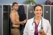 Dr. Moreau (Mike Adler, l.) hat Feierabend und flirtet während des Umziehens mit Kollegin Dr. Sherbaz (Sanam Afrashteh, r.).