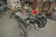 One of the workshop team works on the Citroën 2CV's chassis.