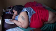 Renee is on her bed reading a book.