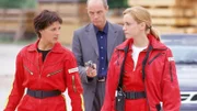 Biggi Schwerin (Sabine Petzl, li.) und Karin Thaler (Roswitha Meyer) werden von Alex Murnau (Andreas Stoek) abgeführt und als Geisel gehalten. Sollte das Medicopter Team sein Geld nicht rausrücken, so ist er bereit, alle zu töten.