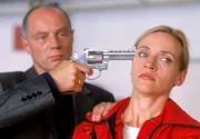 Karin Thaler (Roswitha Meyer) wird von Alex Murnau (Andreas Stoek) mit dem Revolver in Schach gehalten. Der Gangster glaubt, dass das Medicopter-Team im Besitz des Geldes ist und droht sie alle zu töten, wenn er das Geld nicht bekommt.