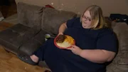 Nicole eats a meal on her couch.
