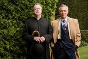 Father Brown (Mark Williams, l.) ist wieder einmal dabei, in einem Mordfall zu ermitteln. Dabei nimmt er den unterkühlten Dennis Nelson (Martin Kemp, r.) besonders genau unter die Lupe.