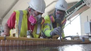 L-R:Greg Gretzner and Chad Gretzner using torch to examine material on gold table in workshop
