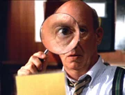 Mit einer Lupe bewappnet sucht Captain Donald Cragen (Dann Florek) nach Spuren. Ob er den gefälschten Ausweis erkennt?