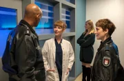 Lukas Petersen (Patrick Abozen, l.) und Nina Sieveking (Wanda Perdelwitz, r.) erkundigen sich bei Dr. Michaela Spaatz (Sarah Bauerett, 2.v.l.) nach dem Zustand des Ehemannes von Anna Diemer (Johanna Chrstine Gehlen, h.).